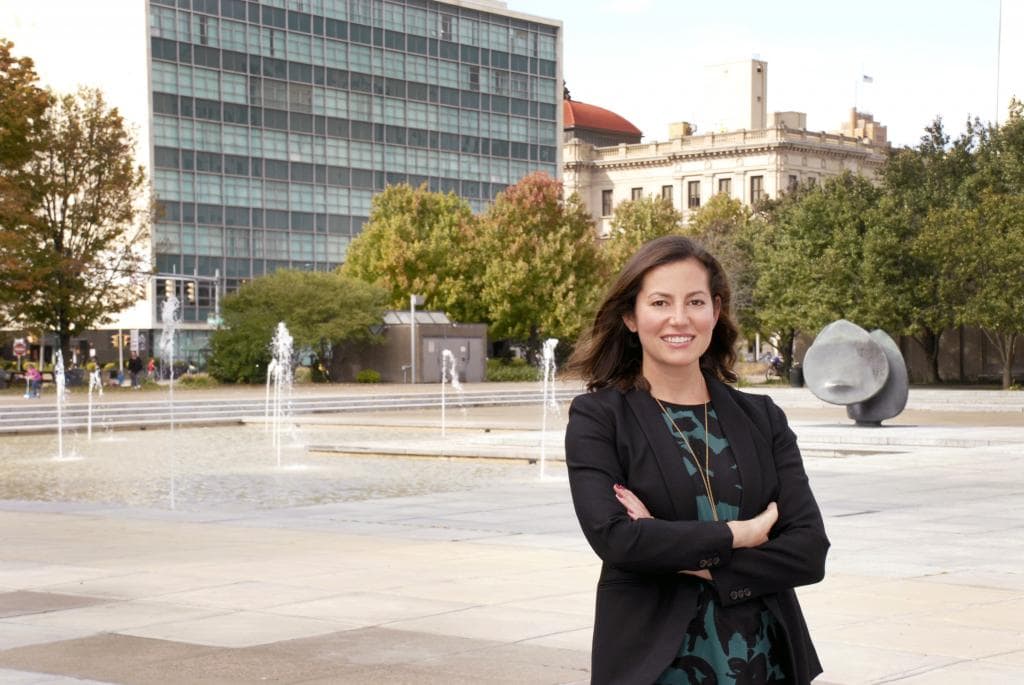 Immigration attorney Rebecca Cohen smiles in front of Syracuse fountains.