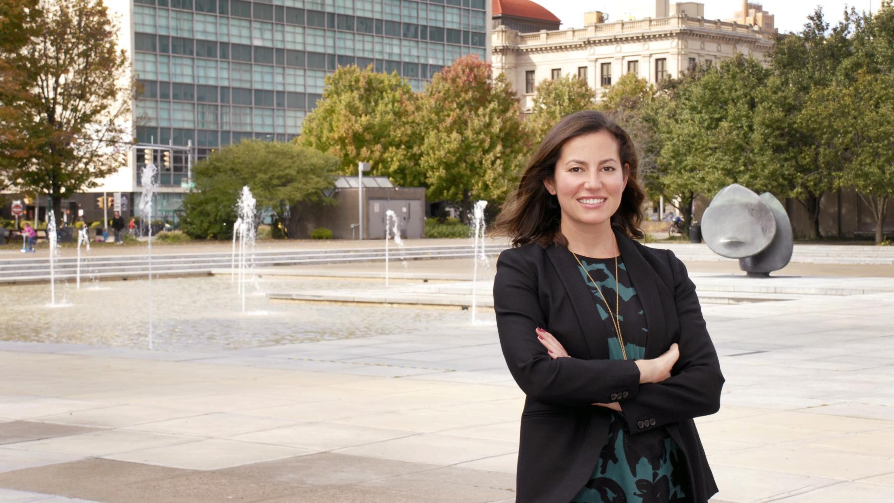 Immigration attorney Rebecca Cohen smiles in front of Syracuse fountains.