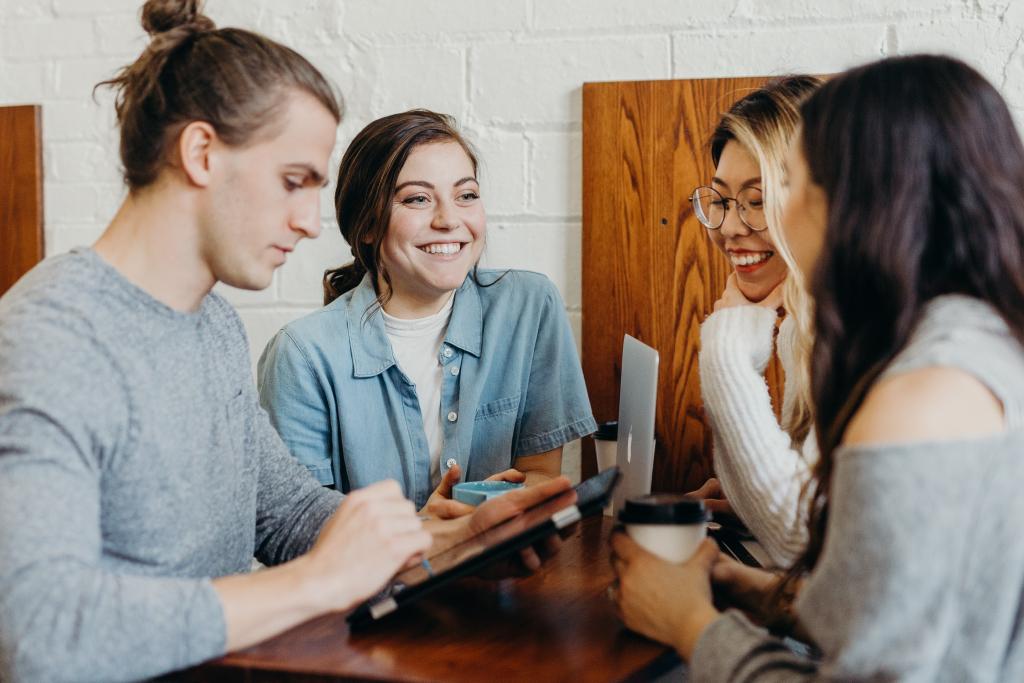 A photo of four students smiling and sitting around a table introduces the Bousquet Holstein International Student Visas practice. 