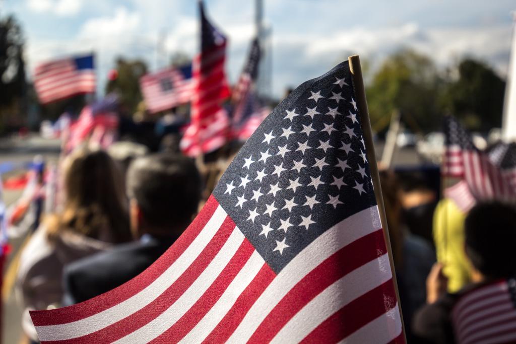 American flags being held by a parade of people. 