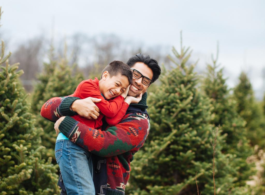 Father picks up his five-year-old son in front of a Christmas tree farm. Navigating Holiday Vacations as Separated Parents. Divorce.